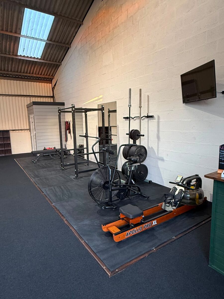 Strength and conditioning area at Forged Grappling, Westbury: power rack, rower and air bike